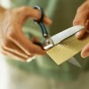 close-up of human hands cutting a credit card by scissors